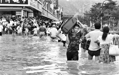 昨日，一名消防戰(zhàn)士在秦皇島市山海關(guān)火車站站前廣場涉水幫助旅客運送行李。 新華社發(fā)