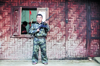 老三手持自己在前線用的半自動(dòng)步槍站在居住的小屋外。