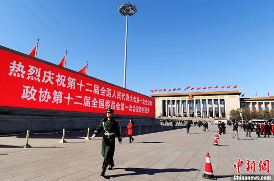 3月4日，北京晴空萬里，武警從北京天安門廣場(chǎng)大型顯示屏前走過。3月5日上午，十二屆全國人大一次會(huì)議將隆重開幕。中新社發(fā) 劉忠俊 攝